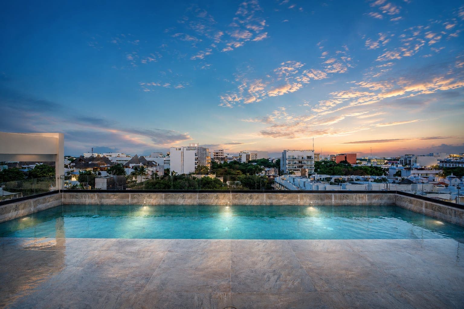 La alberca del rooftop de Marbella al atardecer, con Playa del Carmen y el cielo detrás