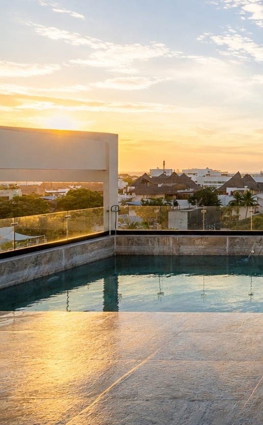 The sun setting over Marbella's rooftop pool, with Playa del Carmen behind