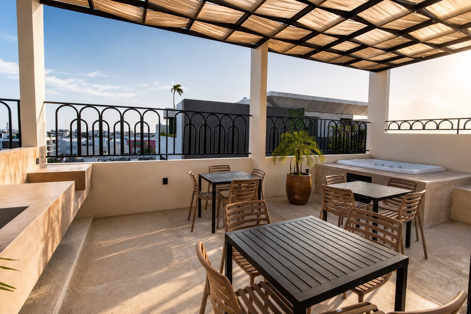 El comedor del rooftop de Marbella bajo la pérgola, con la tina de hidromasaje al fondo