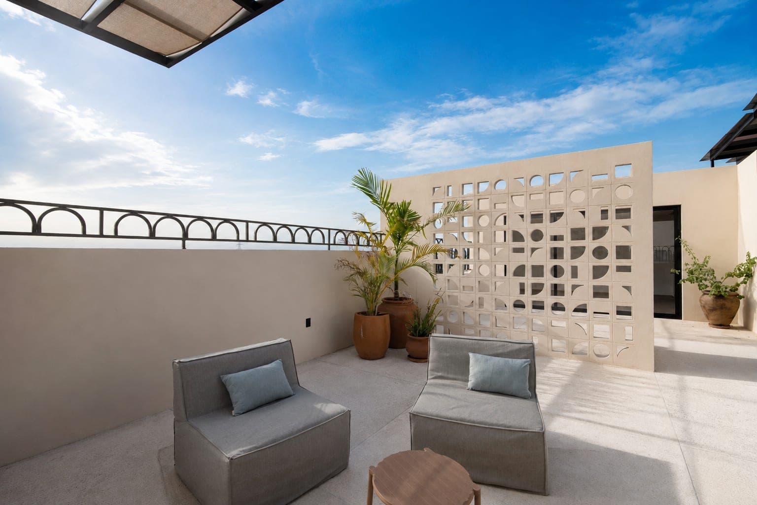 Sillones y mesa baja en el rooftop de Marbella, junto al muro de celosía
