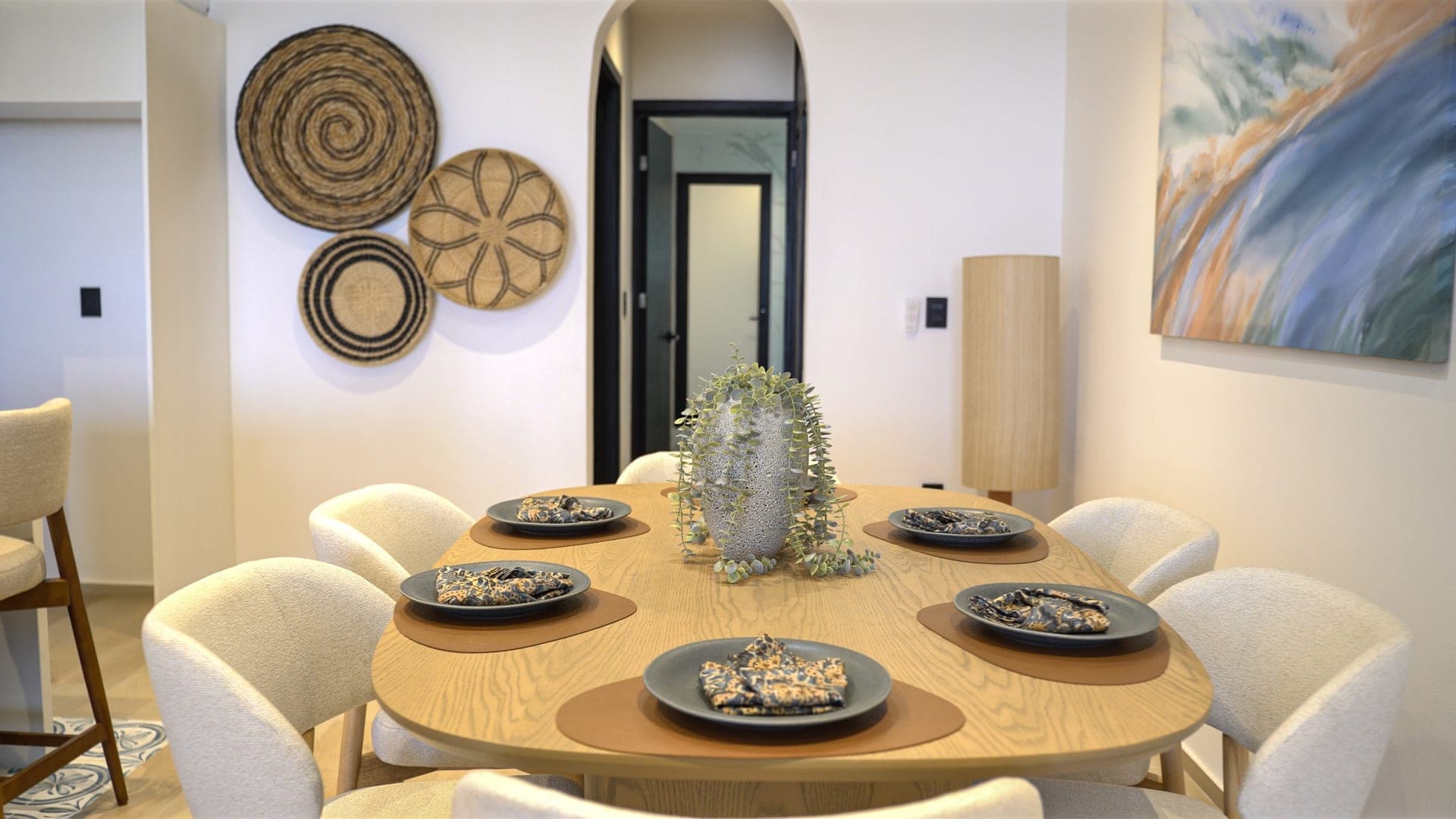 El comedor del penthouse Edúlis puesto para seis, con sillas de bouclé crema y las canastas tejidas al fondo