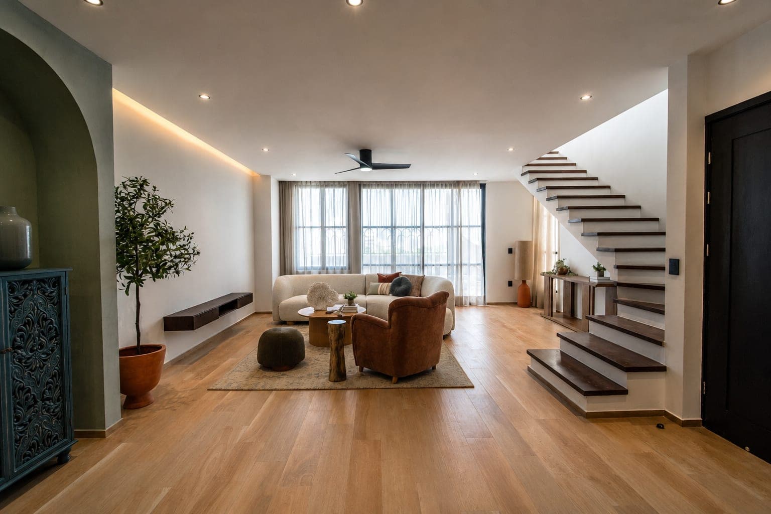 The living area of the Edúlis penthouse facing the window wall, with the stair on the right