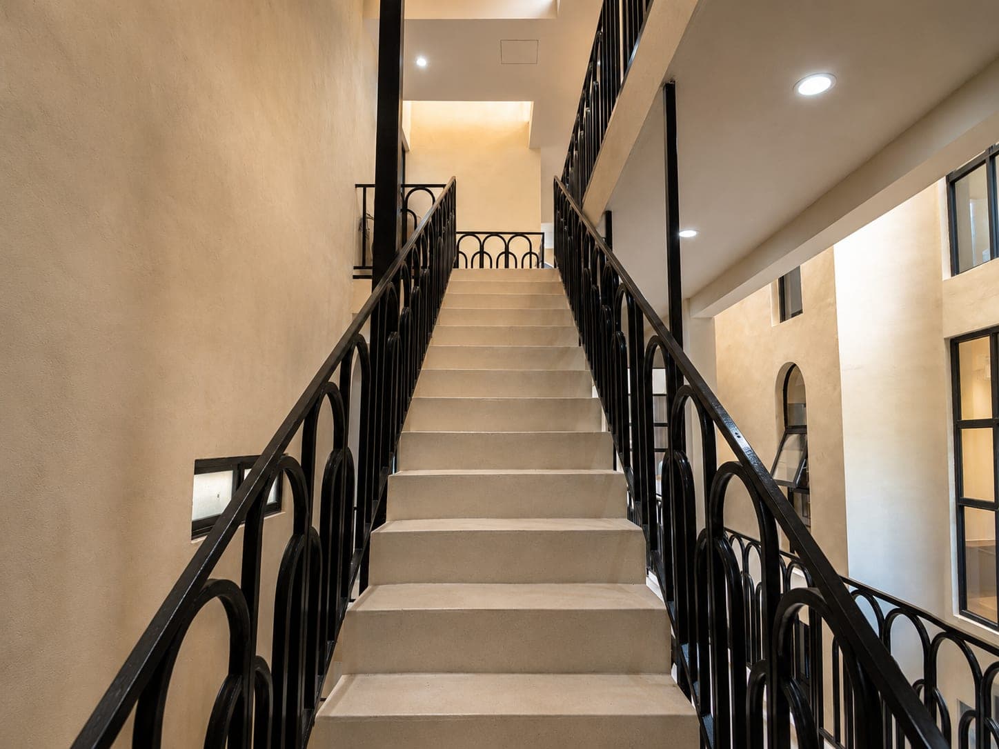 Escalera del edificio, con barandal negro de arcos a los dos lados